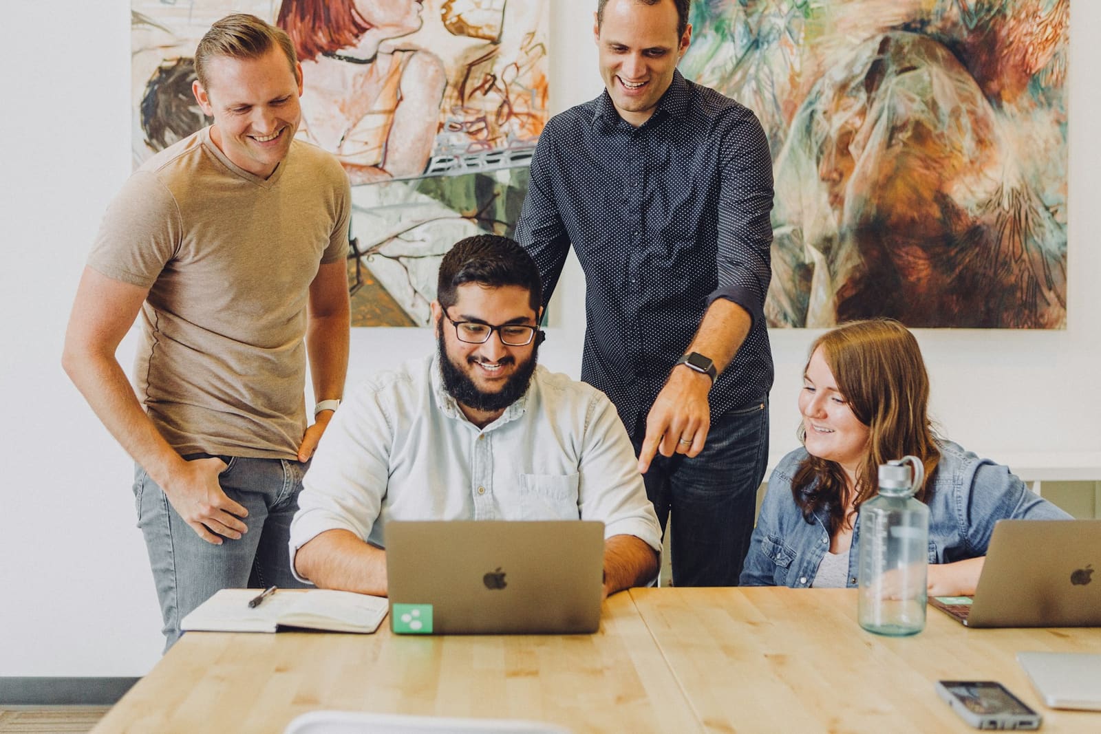 Four engineers working together around a laptop